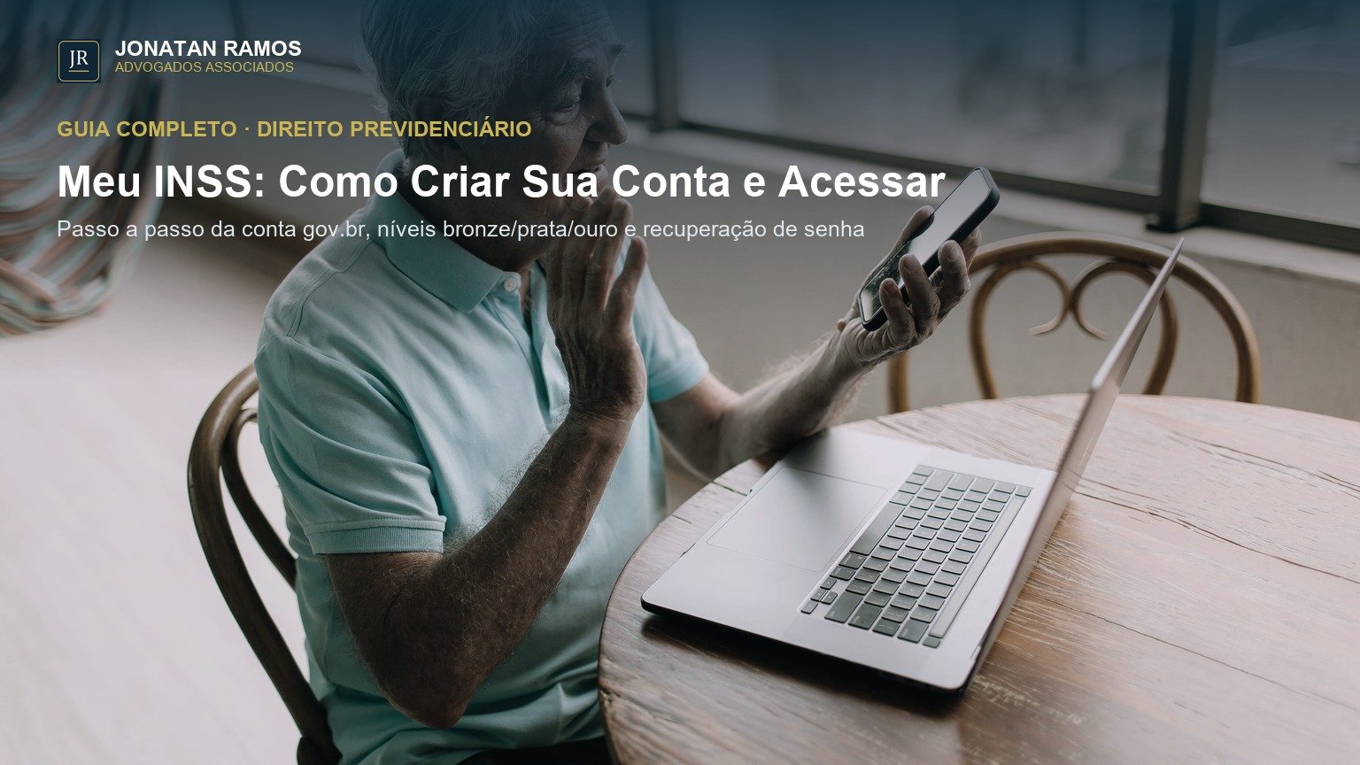 Senhor idoso segurando o celular e mexendo no laptop em uma mesa de madeira